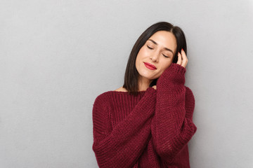 Fototapeta premium Woman dressed in burgundy sweater posing isolated over grey wall background.