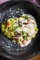  Risotto with porcini mushrooms, sauce, sun-dried tomatoes and pea sprouts on a beautiful clay deep dish of gray color