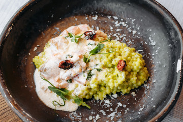  Risotto with porcini mushrooms, sauce, sun-dried tomatoes and pea sprouts on a beautiful clay deep dish of gray color