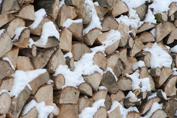 Stacked pieces of tree covered with snow. Chopped tree. Ready wood for winter.