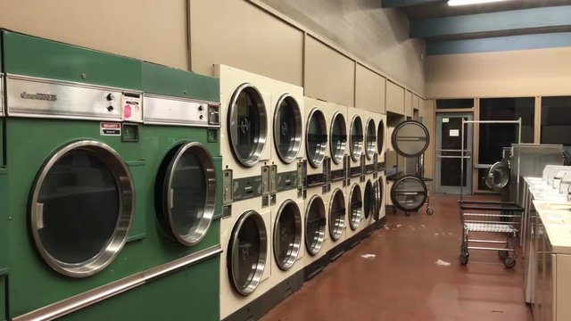 4k UHD handheld footage of a clean, brightly lit, empty Laundromat shot from outside at night