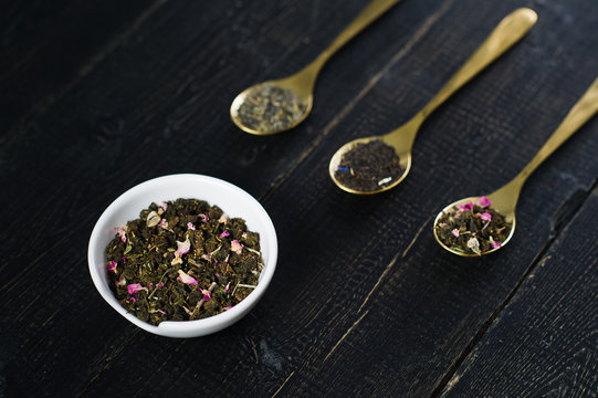 Three Teas, Black, Green, Rooibos In Gold Spoons On Black Wooden Background, Side View