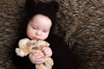 Little baby boy with knitted brown jumpsuit as a bear, sleeping at home