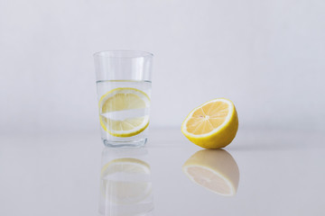 A glass of fresh cool water with lemon slices on a white background