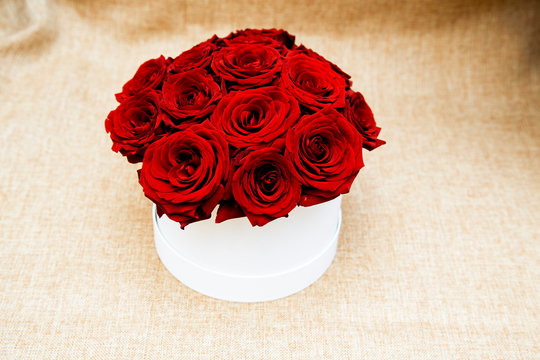 on a light beight background a white box with 15 red roses