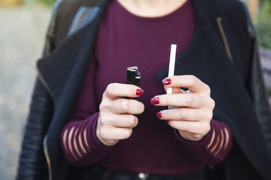 Woman holding cigarette with lighter. Quit smoking concept