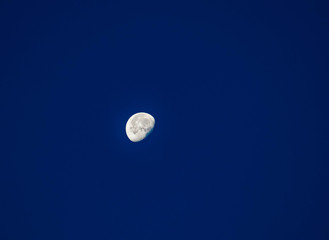 A scary white waning moon with craters on a dark sky, mystical night background.