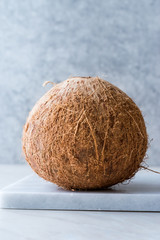 Fresh Organic Brown Raw Coconut on White Marble Board.