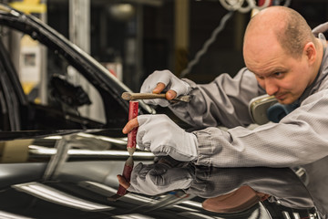 Employee car body painting shop eliminates a small metal defect