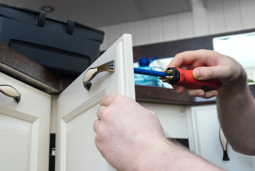 Professional handyman assembling kitchen door cabinet.