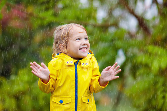 Kids play in autumn rain. Child on rainy day.