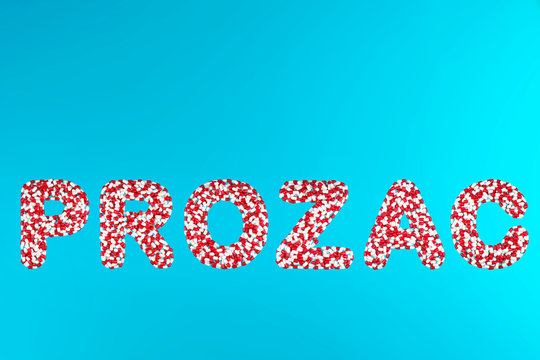 inscription prozac white and red pills on a blue background top view. concept of stress relieving antidepressants painkillers