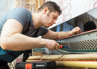 Professional master tuning the piano with ratchet tool.
