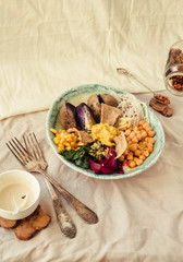Buddha bowl recipe with roasted spinach, sweet purple potatoes, corn, beet, chickpeas and raw vegetables. Selective focus.