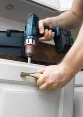 Professional handyman assembling kitchen door cabinet.