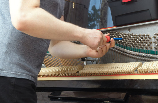 Professional master tuning the piano with ratchet tool.