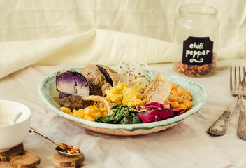 Vegan detox lunch with a purple potato, stewed spinach, and hummus with corn crackers.
