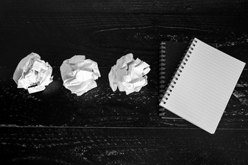 set of scrunched paper balls and empty notepad on dark moody background