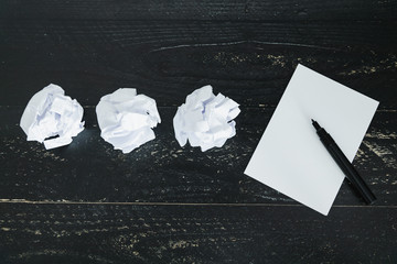 set of scrunched paper balls and empty notepad on dark moody background