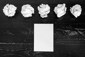 set of scrunched paper balls and empty notepad on dark moody background