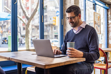 Middle aged businessman in a coffee shop with his computer