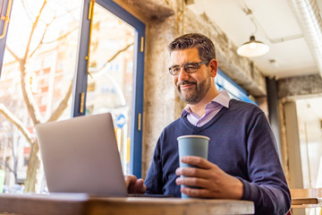 Middle aged businessman in a coffee shop with his computer