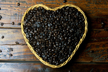 roasted coffee beans inside basket with heart shape on rustic wooden table