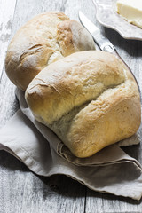 Zwei Brötchen mit Butter, Messer und Serviette, rustikal