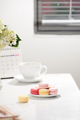 Office table desk. Feminine desk workspace frame with calendar, diary, hortensia bouquet, macaron and coffee on white background. ideas, notes or plan writing concept