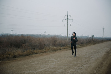 Obraz premium A man runs in headphones on the road. Stroke in pants and sneakers