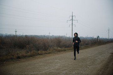 A man runs in headphones on the road. Stroke in pants and sneakers