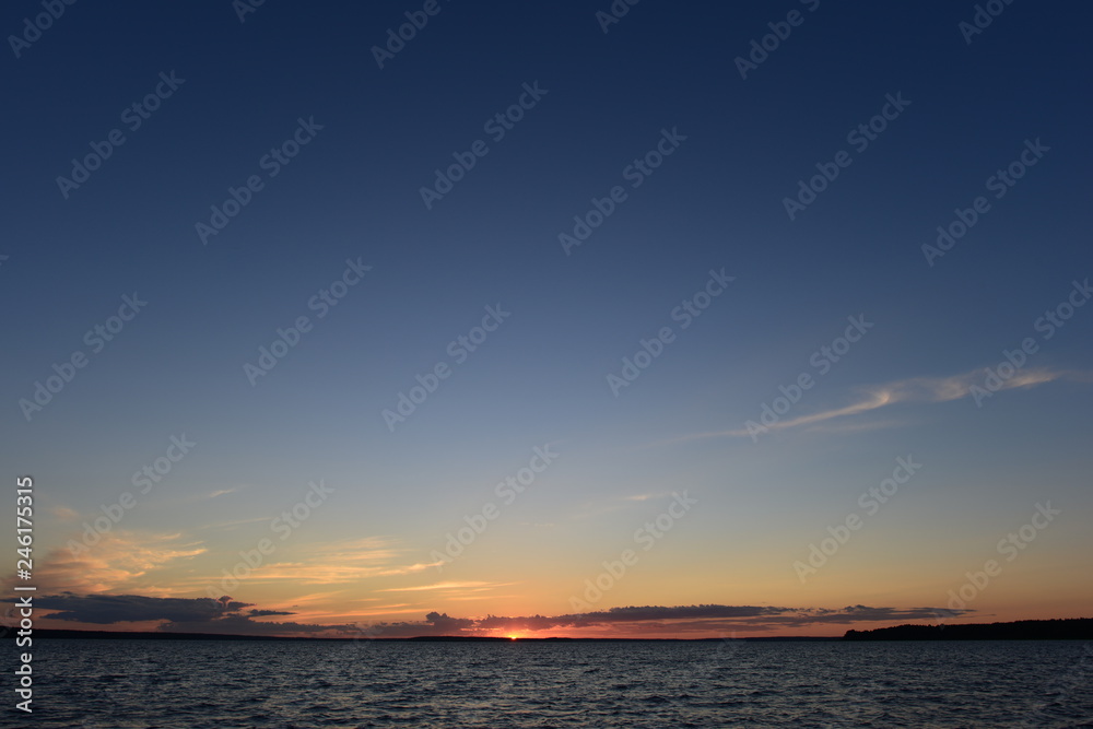 Wall mural sunset is a small bright point on the horizon the sun is infinite in space the blue of the sky and t
