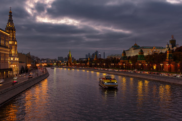 Fototapeta na wymiar Pleasure boat on Moskva river near Moscow Kremlin in evening on a background of dramatic cloudy sky. City landscape