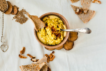 Bowl of fresh fish pate beside chips, corn crackers and walnuts.