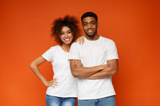 Young african-american couple posing on orange background