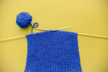Bright knitted  scarf with knitting needles. On green background. Minimalism top view contrast....