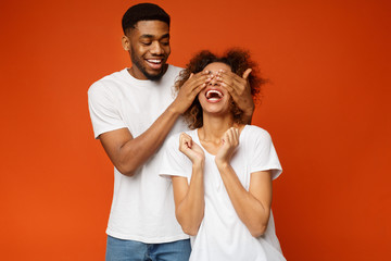 Black man standing behind his girlfriend and closing her eyes