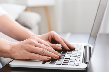 Fototapeta na wymiar Old woman working on laptop computer at home