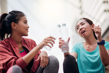 Beautiful fitness athlete asian woman drinking water after exercise.