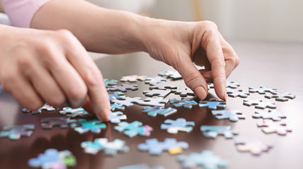 Elderly woman hands doing jigsaw puzzle closeup - obrazy, fototapety, plakaty