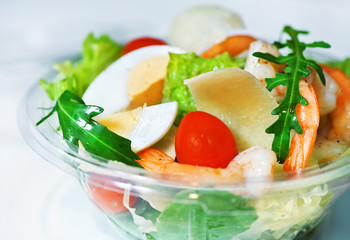 Delicious Caesar salad with shrimps, tomatoes and arugula on white