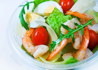 Delicious Caesar salad with shrimps, tomatoes and arugula on white