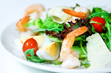 Delicious Caesar salad with shrimps, tomatoes and arugula on white