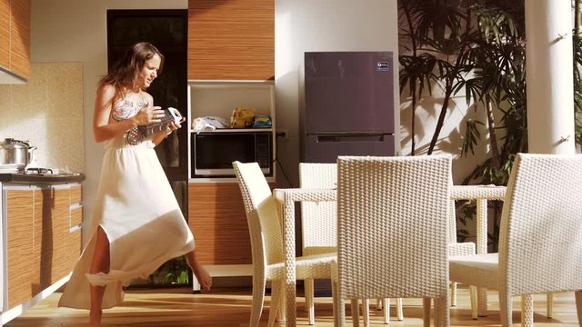 Happy young woman has fun singing and dancing in the kitchen with grater while making breakfast. 3840x2160