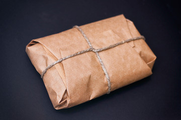 Craft wrapped package on black background. Parcel with hemp cord. 