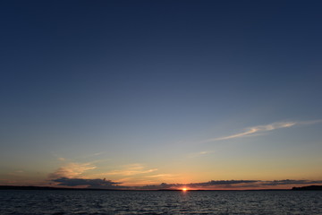 Fototapeta na wymiar Sunset at the water level of the lake on the horizon the last sunlight of the sun
