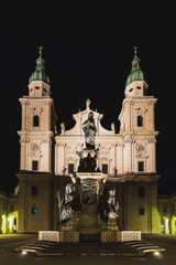 Fototapeta na wymiar Kirche mit zwei Glockentürmen und Barockfassade in der Dunkelheit mit Licht angestrahlt
