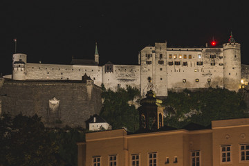 Fototapeta na wymiar Bild einer Stadt bei Dunkelheit mit einer Burg mit weißen Gebäuden Mauern und Turm auf Berg