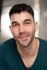 Obraz premium Handsome caucasian white male with black short hair and stubble with blue t shirt with a smirk