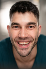 Obraz premium Handsome caucasian white male with black short hair and stubble with blue t shirt smiling